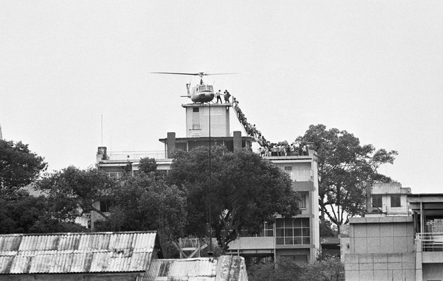 A CIA employee helps Vietnamese evacuees onto an Air America helicopter from the top of 22 Gia Long Street, a half mile from the U.S. embassy, on April 29, 1975, shortly before Saigon fell to the advancing North Vietnamese army. (Photo by Bettmann Archive)