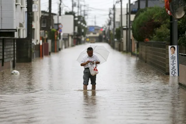 A man wades through a residential area flooded by the Kinugawa river, caused by typhoon Etau, in Joso, Ibaraki prefecture, Japan, September 10, 2015. (Photo by Issei Kato/Reuters)