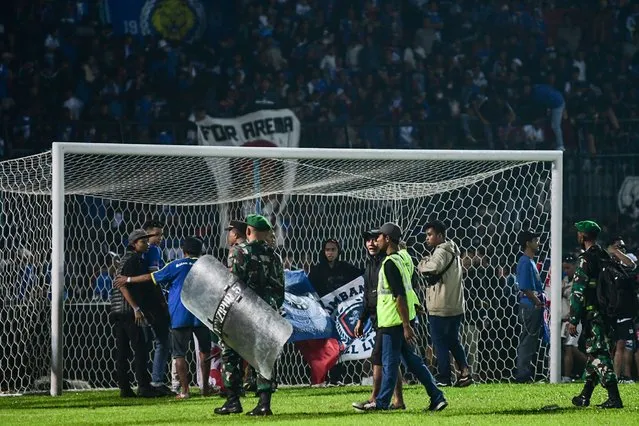 This picture taken on October 1, 2022 shows Indonesian army and police securing the pitch after a football match between Arema FC and Persebaya Surabaya at Kanjuruhan stadium in Malang, East Java. At least 127 people died at a football stadium in Indonesia late on October 1 when fans invaded the pitch and police responded with tear gas, triggering a stampede, officials said. (Photo by AFP Photo/Stringer)