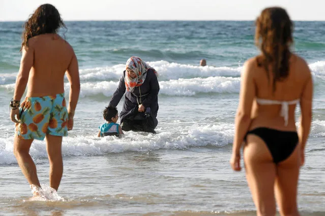 A Muslim woman wearing a Hijab stands in the waters in the Mediterranean Sea as Israelis stand nearby on the beach in Tel Aviv, Israel August 22, 2016. (Photo by Baz Ratner/Reuters)