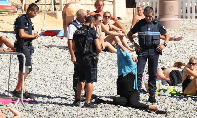 Police patrolling the Promenade des Anglais beach in Nice, France on August 24, 2016, fine a woman for wearing a burkini. (Photo by VantageNews.com)