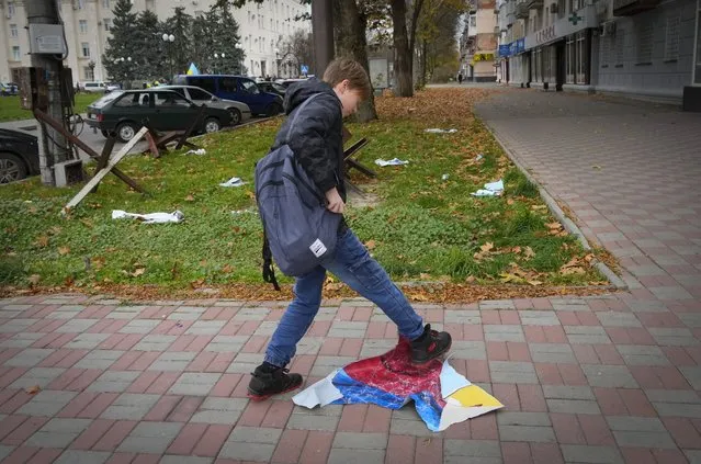 A boy tramples the Russian flag in central Kherson, Ukraine, Sunday, November 13, 2022. (Photo by Efrem Lukatsky/AP Photo)