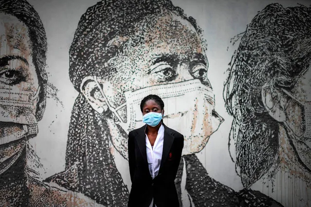 Technical assistant Cristina Teixeira poses before Portuguese artist Alexandre Farto aka Vhils' mural depicting her face carved on a wall of Sao Joao Hospital in Porto on June 17, 2020. Vhils unveiled on June 19, 2020 this carving-graffiti artwork at the Sao Joao hospital that pays tribute to the health professionals who were at the frontline fighting the novel coronavirus outbreak. (Photo by Patrícia de Melo Moreira/AFP Photo)