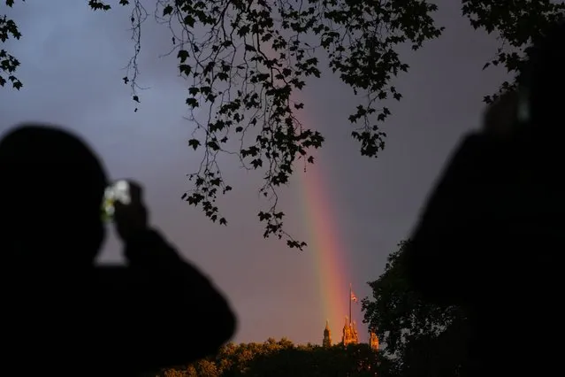 People take pictures of a rainbow over the Houses of Parliament on the eve of the funeral of Queen Elizabeth II in London, England, Sunday, September 18, 2022. Queen Elizabeth II, Britain's longest-reigning monarch and a rock of stability across much of a turbulent century, died Thursday Sept. 8, 2022, after 70 years on the throne. She was 96. (Photo by Petr David Josek/AP Photo)