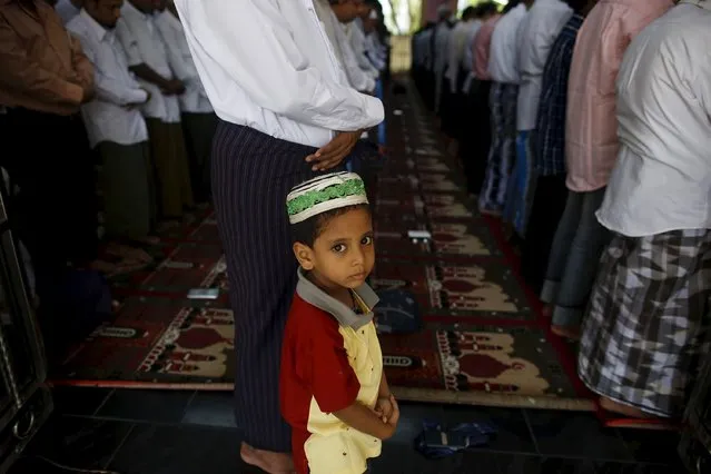 A boy stands next to Muslims performing the Eid al-Adha prayer at a mosque in Yangon, Myanmar September 25, 2015. (Photo by Soe Zeya Tun/Reuters)