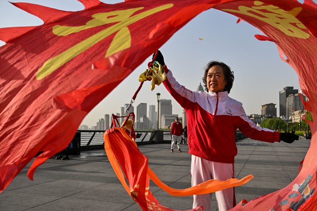 A woman twirls a dragon streamer on the Bund promenade along the Huangpu River during sunrise in Shanghai on April 14, 2025. US President Donald Trump warned April 13 that no country would be getting “off the hook” on tariffs despite a 90-day reprieve on some levies, while also downplaying exemptions for Chinese technology. (Photo by Hector Retamal/AFP Photo)