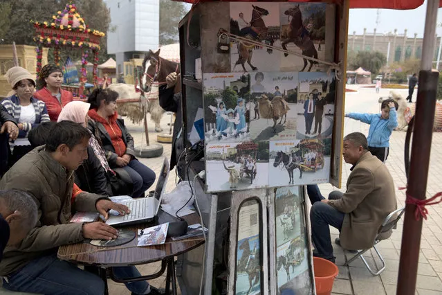 In this November 4, 2017, photo, vendors selling photography services for tourists work near the Id Kah Mosque in Kashgar in western China's Xinjiang region. Authorities are using detentions in political indoctrination centers and data-driven surveillance to impose a digital police state in the region of Xinjiang and its Uighurs, a 10-million strong, Turkic-speaking Muslim minority Beijing fears could be influenced by extremism. (Photo by Ng Han Guan/AP Photo)