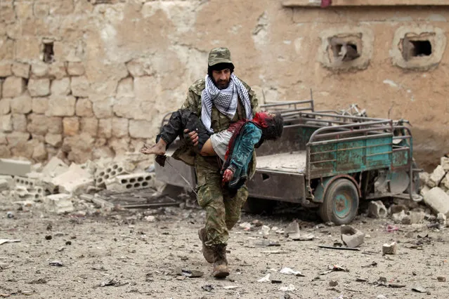A rebel fighter carries an injured boy after a car bomb explosion in Jub al Barazi east of the northern Syrian town of al-Bab, Syria, January 15, 2017. (Photo by Khalil Ashawi/Reuters)