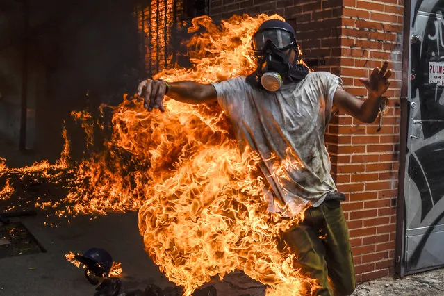 A demonstrator catches fire after the gas tank of a police motorbike exploded during clashes in a protest against Venezuelan President Nicolas Maduro, in Caracas on May 3, 2017. Venezuela's angry opposition rallied Wednesday vowing huge street protests against President Nicolas Maduro's plan to rewrite the constitution and accusing him of dodging elections to cling to power despite deadly unrest. (Photo by Juan Barreto/AFP Photo)