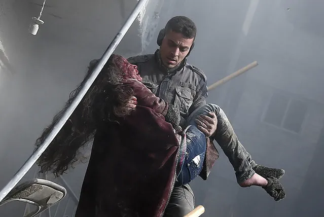 A volunteer from the Syrian Civil Defence (known as the White Helmets) carries a wounded girl after digging her out of the rubble following an air strike on Hamouria, in the besieged rebel-held Eastern Ghouta area near Damascus, on January 9, 2018. Air strikes and artillery fire killed over a dozen civilians in a besieged rebel enclave near Damascus targeted by near-daily regime bombardment, a war monitor said. (Photo by Abdulmonam Eassa/AFP Photo)