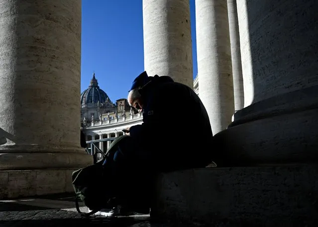 A nun sits under the columns in St Peter's Square at The Vatican on December 28, 2022. Former pontiff Benedict XVI, 95, is “very ill”, Pope Francis said on December 28, as he urged people to pray for him before going to be by his side. (Photo by Filippo Monteforte/AFP Photo)
