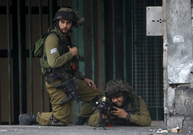 An Israeli army soldier aims his weapon at Palestinians during clashes in the West Bank city of Hebron October 9, 2015. (Photo by Mussa Qawasma/Reuters)