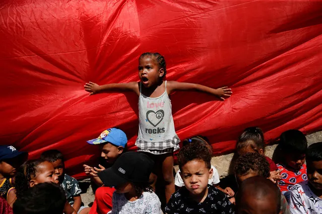 A girl reacts while waiting in line to participate in a distribution of toys for children in a low-income neighborhood, in Caracas, Venezuela on December 17, 2022. (Photo by Leonardo Fernandez Viloria/Reuters)