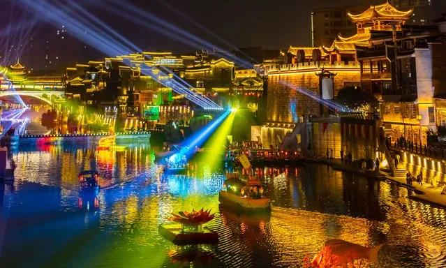 Tourists visit the illuminated Qianzhou Ancient Town to celebrate Chinese New Year, the Year of the Rabbit, at night on February 1, 2023 in Jishou, Xiangxi Tujia and Miao Autonomous Prefecture, Hunan Province of China. (Photo by VCG/VCG via Getty Images)