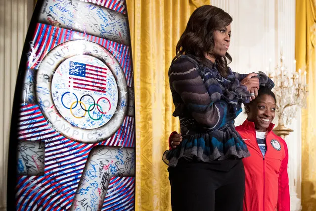 First lady Michelle Obama jokingly uses the head of US Olympics gymnast Simone Biles as an arm rest as they take the stage in the East Room of the White House in Washington, Thursday, Sept. 29, 2016, during a ceremony where President Barack Obama honored the 2016 United States Summer Olympic and Paralympic Teams. (AP Photo/Andrew Harnik)