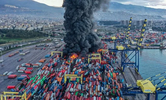 This handout photograph taken and released by Turkish agency DHA (Demiroren News Agency) shows smoke rising from burning containers at the harbor of Iskenderun in Hatay, a day after a 7.8-magnitude earthquake struck the country's southeast, on February 7, 2023. Rescuers in Turkey and Syria braved frigid weather, aftershocks and collapsing buildings, as they dug for survivors buried by an earthquake that killed more than 5,000 people. Some of the heaviest devastation occurred near the quake's epicentre between Kahramanmaras and Gaziantep, a city of two million where entire blocks now lie in ruins under gathering snow. (Photo by Handout/DHA (Demiroren News Agency) via AFP Photo)