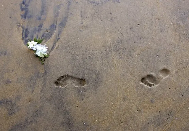 A rose which was thrown into the waters of the Andaman Sea to mark the one-year Indian Ocean tsunami anniversary lies near footprints in Khao Lak, located in Thailand's Phang Nga province, north of the resort island of Phuket in this December 26, 2005 file photo. (Photo by Adrees Latif/Reuters)