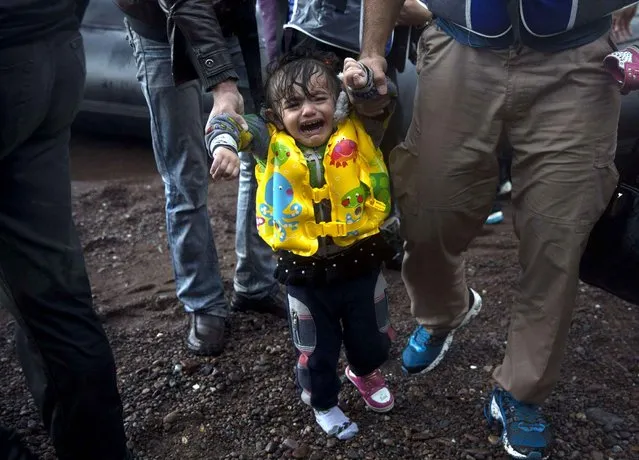 A young girl with a lost shoe cries after her arrival on a dinghy with her family from the Turkish coast to Skala Sikaminias village on the northeastern Greek island of Lesbos, Wednesday, October 21, 2015. Greece is the main entry point for those fleeing violence at home and seeking a better life in the European Union. More than 500,000 people have arrived so far this year on Greece's eastern islands, paying smugglers to ferry them across from nearby Turkey. (Photo by Santi Palacios/AP Photo)