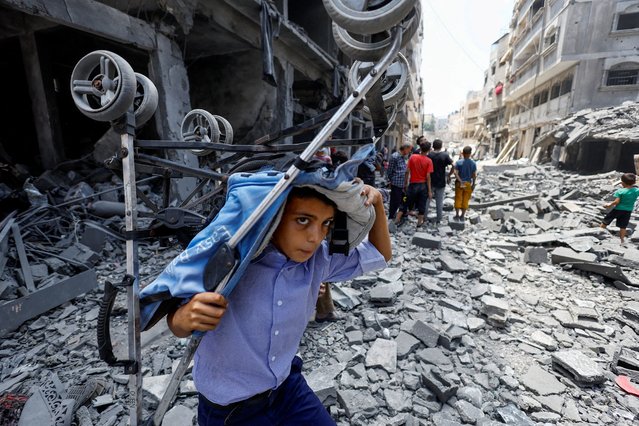 A Palestinian boy carries a stroller at the site of a morning Israeli strike on a house, in Gaza City on August 8, 2025. (Photo by Mahmoud Issa/Reuters)