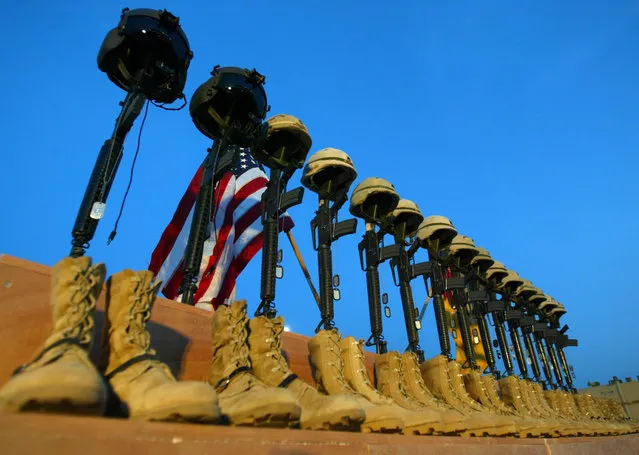 A row of U.S. Army helmets perched on M-16 rifles during a memorial at Al Asad air base for the 15 victims of a Chinook helicopter shot down by insurgents, November 6, 2003. (Photo by Chris Helgren/Reuters)