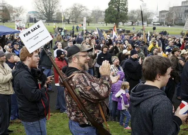 Jack Thompson (carrying rifle) of Yacolt, Washington, who says he bought his rifle in defiance of state Initiative 594, applauds as gun rights advocates rally at the state capitol in Olympia, Washington December 13, 2014. Initiative 594, which requires background checks for all gun purchases in Washington state, was voted into law last month, making the state the first in the country to close the so-called gun-show loophole through popular vote. (Photo by Jason Redmond/Reuters)