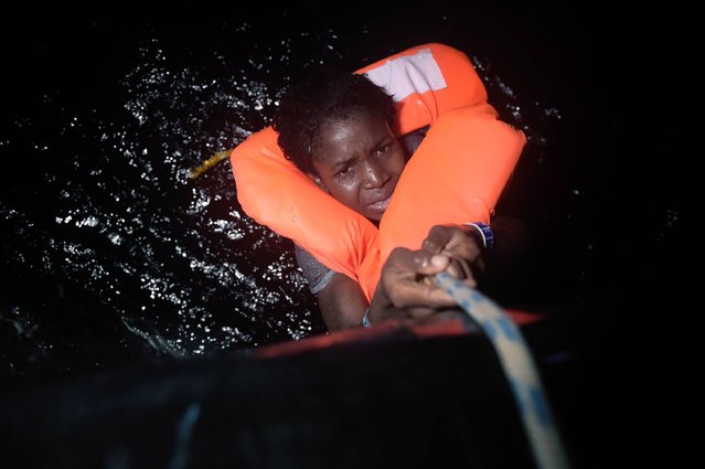A migrant holds onto a rope during a rescue operation some eight nautical miles off Libya's Mediterranean coastline on October 12, 2016. A growing number of people are attempting the treacherous sea journey from Libya or Egypt, after the closure of the Balkan migrant trail route leading from Greece to western Europe. (Photo by Aris Messinis/AFP Photo)