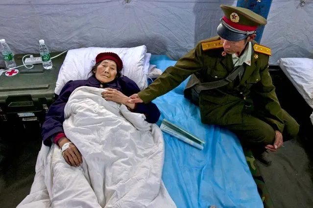 A soldier looks after an elderly relative resting in a military field hospital in Lushan, China following an earthquake that killed 200 people, on April 22, 2013. (Photo by Ng Han Guan/Associated Press)