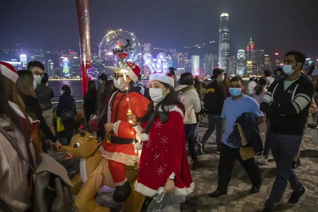 People wearing Christmas costumes and protective masks to prevent the spread of coronavirus, walk at the waterfront of Victoria Harbour,  in Hong Kong, Thursday, December 24, 2020. (Photo by Kin Cheung/AP Photo)
