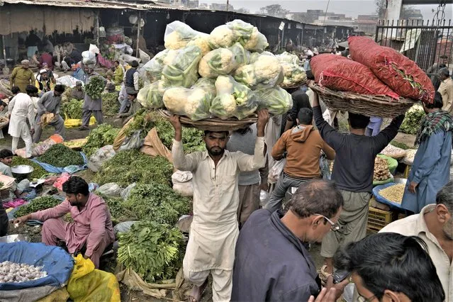 Laborers work at a wholesale vegetable and fruit market in Lahore, Pakistan, Friday, February 17, 2023. Many laborers are worried how they will survive after the government advanced a bill to raise 170 billion rupees in tax revenue. That could worsen impoverished Pakistan's economic outlook as it struggles to recover from devastating summer floods and a wave of violence. (Photo by K.M. Chaudary/AP Photo)