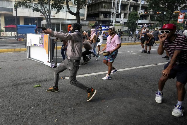 A protester aims a weapon during clashes with police during demonstrations against the official election results declaring President Nicolas Maduro's reelection in Caracas, Venezuela, Monday, July 29, 2024, the day after the vote. (Photo by Fernando Vergara/AP Photo)