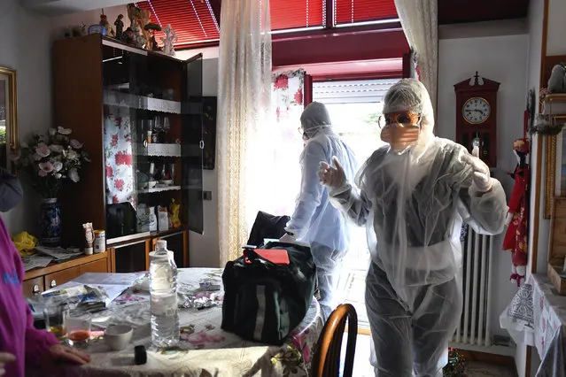 Medical staffers wearing protective gear, part of a special unit performing house calls, work in Bergamo, northern Italy, one of the areas worse-affected by coronavirus, Wednesday, March 25, 2020. (Photo by Claudio Furlan/LaPresse via AP Photo)