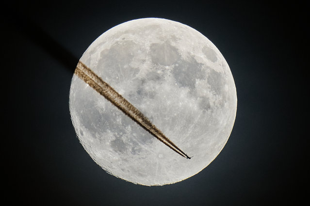 An aircraft passes the moon over Frankfurt, Germany, Tuesday, November 4, 2025. (Photo by Michael Probst/AP Photo)