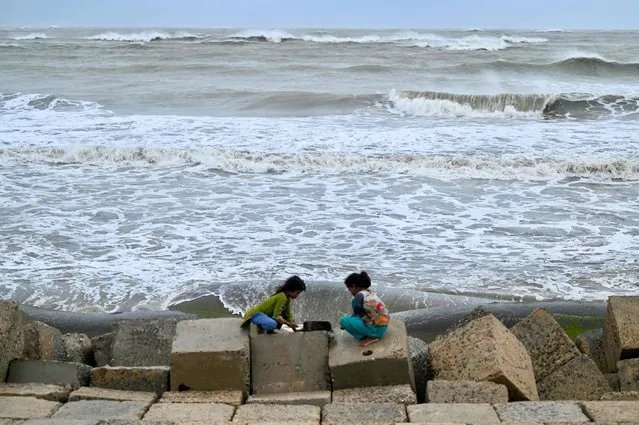 Children play on an embankment in Shahpori island on the outskirts of Teknaf, on May 14, 2023, ahead of Cyclone Mocha's landfall. Thousands fled Myanmar's west coast and officials in neighbouring Bangladesh raced to evacuate Rohingya refugees on May 13 as the most powerful cyclone in the region for over a decade churned across the Bay of Bengal. (Photo by Munir Uz Zaman/AFP Photo)