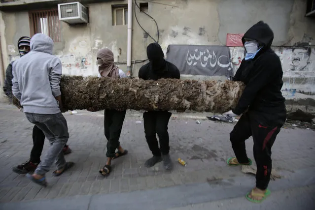 Bahraini anti-government protesters carry a palm tree trunk to block a street from police during a demonstration against Saudi Arabia's execution of Shiite cleric Sheikh Nimr al-Nimr, in Daih, Bahrain, Saturday, January 2, 2016. Saudi Arabia announced Saturday it had executed 47 prisoners convicted of terrorism charges, including al-Qaida detainees and al-Nimr, who rallied protests against the Saudi government. The execution of al-Nimr is expected to deepen discontent among Saudi Arabia's Shiite minority and heighten sectarian tensions across the region. (Photo by Hasan Jamali/AP Photo)