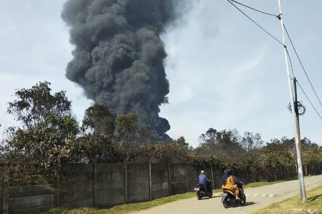 Motorists ride past as thick smoke billows from a fire that razes through Pertamina Balongan Refinery in Indramayu, West Java, Indonesia, Monday, March 29, 2021. (Photo by AP Photo/Stringer)