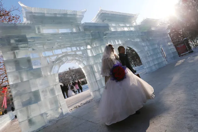 Newly wed couple walk past an ice sculpture during a mass wedding ceremony of the 32nd Harbin International Ice and Snow Festival in Zhaolin Park in Harbin city, China's northern Heilongjiang province, 06 January 2016. As many as 15 couples attend this mass wedding ceremony. The festival official opens on 05 January and lasts to 05 February that attracting both foreign and local visitors to experience the ice and snow. (Photo by Wu Hong/EPA)