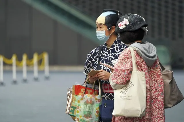A person with a protective mask to help curb the spread of the coronavirus wears samurai wig Tuesday, April 6, 2021, in Tokyo. The Japanese capital confirmed more than 390 new coronavirus cases on Tuesday. (Photo by Eugene Hoshiko/AP Photo)