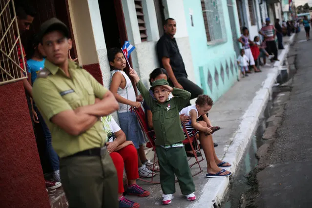 A child salutes while waiting with others for the ashes of Cuba's former President Fidel Castro to pass during a journey to the eastern city of Santiago de Cuba, in Bayamo, Cuba, December 2, 2016. (Photo by Edgard Garrido/Reuters)
