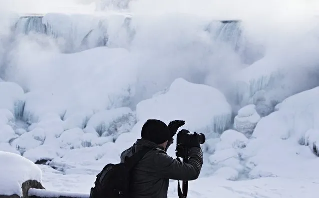 A man photographs ice masses formed around the American Falls as seen from Niagara Falls, Ontario, Canada, Thursday, February 19, 2015. (Photo by Aaron Lynett/AP Photo/The Canadian Press)
