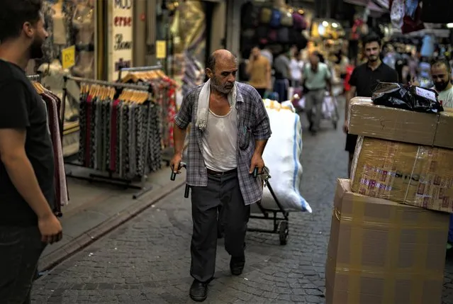 A man pulls a trolley with goods in a street market in Eminonu commercial district in Istanbul, Turkey, Wednesday, August 23, 2023. (Photo by Khalil Hamra/AP Photo)