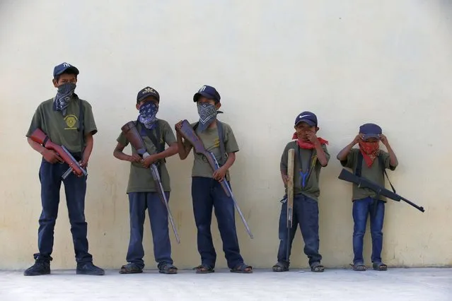 Children hold their training weapons, some real and some fake, during a display for the media designed to attract the federal government's attention to the dangers of organized crime that their town negotiates daily in Ayahualtempa, Guerrero state, Mexico, Wednesday, April 28, 2021. International organizations have condemned the “recruitment” of children and warned of the effects. (Photo by Marco Ugarte/AP Photo)