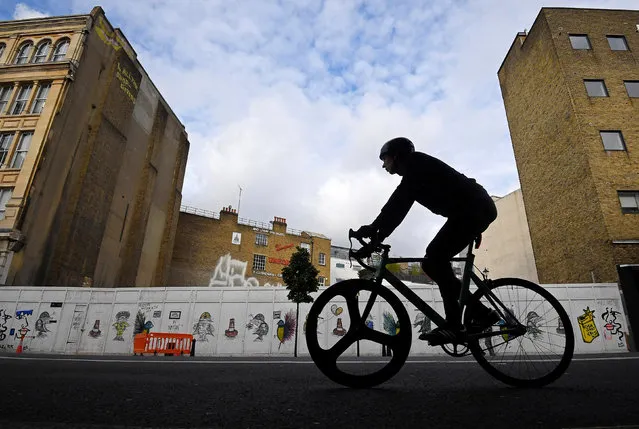 A cyclist rides past a boarded-up petrol station, used as an open-air cinema as well as a car wash since its closure, now awaiting commercial redevelopment in a prime real estate location in the Clerkenwell district of central London, Britain, October 26, 2016. (Photo by Toby Melville/Reuters)