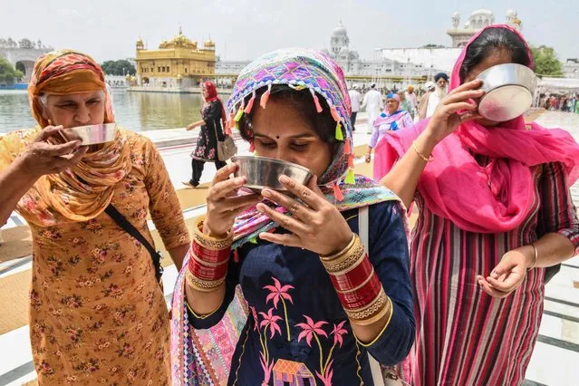 Sikh devotees drink sweet water distributed by volunteers on the occasion of the 415th Martyrdom Day for the Sikh Guru Arjun Dev, at the Golden Temple in Amritsar on June 14, 2021. (Photo by Narinder Nanu/AFP Photo)