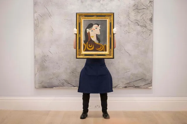A gallery worker poses with an artwork entitled  “Buste de femme à la robe brune” by Spanish painter Pablo Picasso during a photocall at the preview of Sotheby's Major Summer Auctions at Sotheby’s auction house in central London on June 22, 2021. (Photo by Tolga Akmen/AFP Photo)
