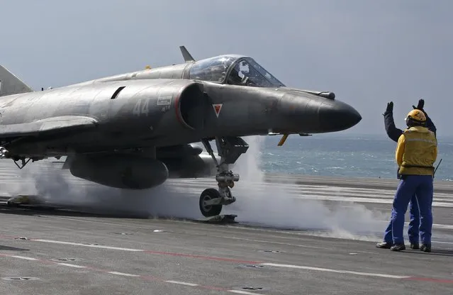 A “Yellow dog” fly deck director and a crew member direct the pilot of a Super Etendard fighter to the catapult minutes before taking of from France's Charles de Gaulle aircraft carrier on mission in the Gulf, January 29, 2016. (Photo by Philippe Wojazer/Reuters)