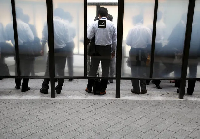 People stand to smoke at a cigarette area at a business district in Tokyo, September 15, 2015. (Photo by Yuya Shino/Reuters)