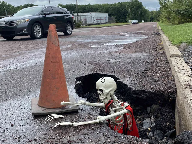 A plastic skeleton peers out a hole on the side of the road on Rotary Drive in Valmont Park in West Hazleton, Pa., on Tuesday, September 6, 2022, as a vehicle passes by. The skeleton drew attention to deteriorated conditions that borough officials plan to address with more than $1.7 million worth of grants. (Photo by John Haeger/Standard-Speaker via AP Photo)