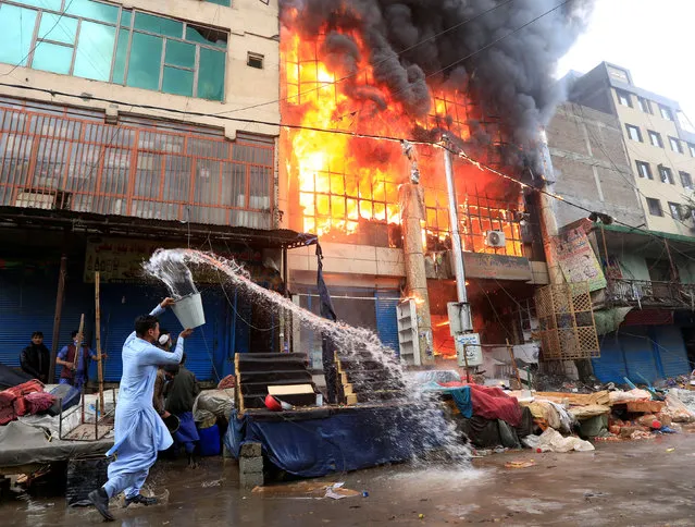 An Afghan man pours water to extinguish a fire at a commercial market in Jalalabad, Afghanistan January 4, 2019. (Photo by Reuters/Parwiz)
