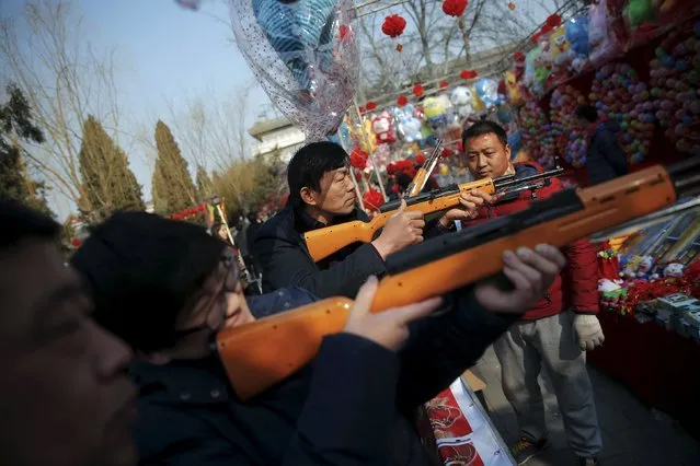 People shoot balloons with plastic guns at a fair at Daguanyuan park as the Chinese Lunar New Year, which welcomes the Year of the Monkey, is celebrated, in Beijing, China February 10, 2016. (Photo by Damir Sagolj/Reuters)