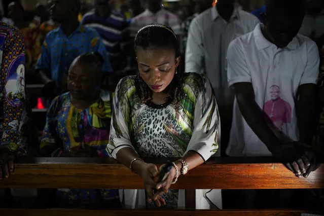 Congolese worshipers listen to Msg. Fridolin Ambongo, the the newly appointed Archibishop of Kinshasa, deliver the homily during an early midnight mass at the Notre Dame du Congo Cathedral in Kinshasa, Congo, Monday December 24, 2018. Ambobgo said that Congolese people must embrace non-violence to make it through Dec. 30th elections. He warned that “The publication of results that would not reflect the will of the people as expressed in the ballot boxes would mean the annihilation of peace in our country”. (Photo by Jerome Delay/AP Photo)